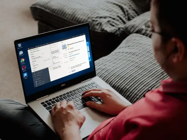 Клієнт використовує 1Password на своєму ноутбуці з Windows, сидячи на дивані.